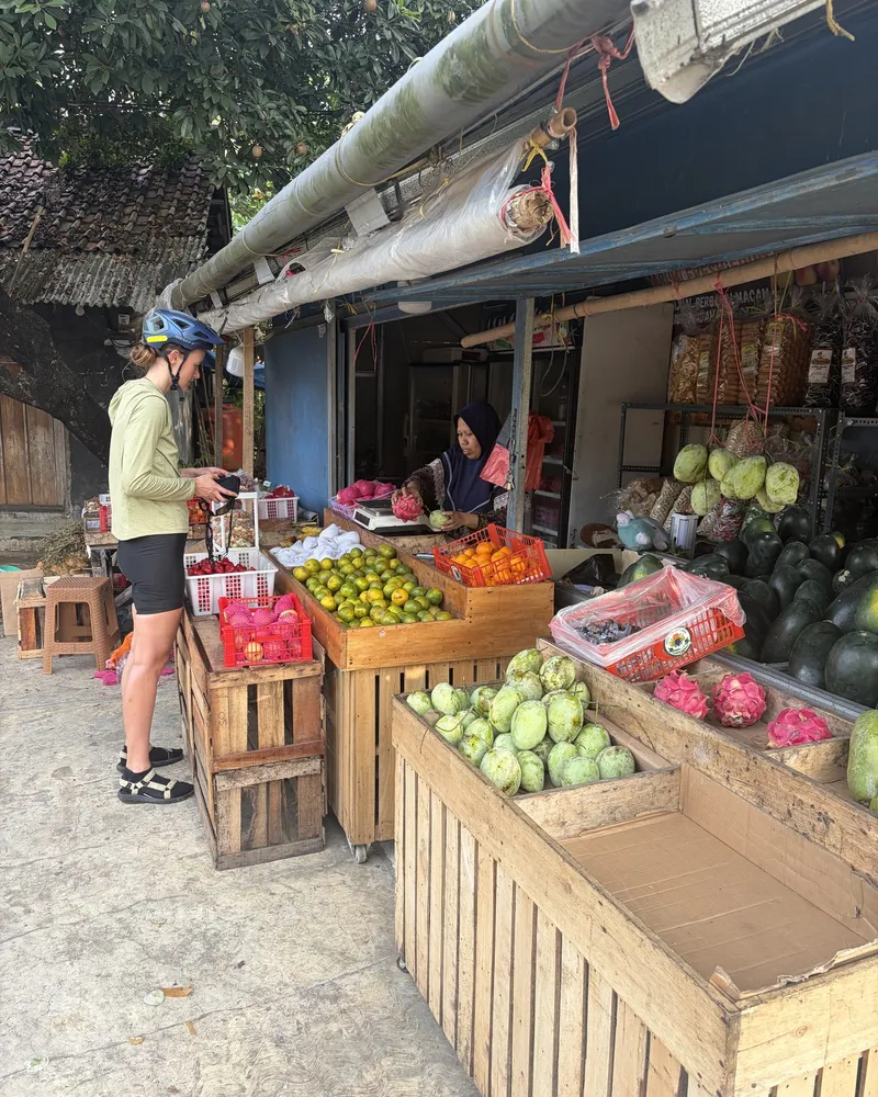 A traveller buying fruit from a local vendor at a roadside market stall